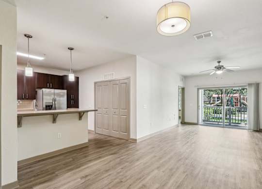 A spacious living room with wooden floors and sliding glass doors that lead to the patio at Oakleaf Plantation Apartments in Jacksonville, FL