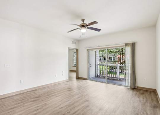 Royal Palm living room with a ceiling fan and sliding glass doors that lead to the patio at Oakleaf Plantation Apartments in Jacksonville, FL