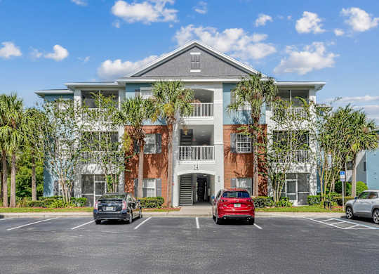A multi-story apartment building with a parking lot in front at Wynnfield Lakes Apartments in Jacksonville, FL