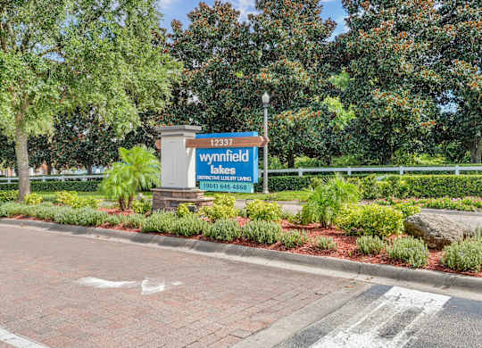 A sign for Wynnfield Lakes is displayed in front of a landscaped area at Wynnfield Lakes Apartments in Jacksonville, FL