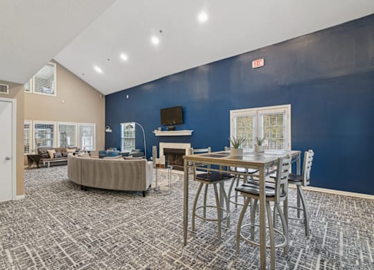 Clubhouse lounge area with couch and a TV above the fireplace at Woodmere Trace apartments in Duluth, GA