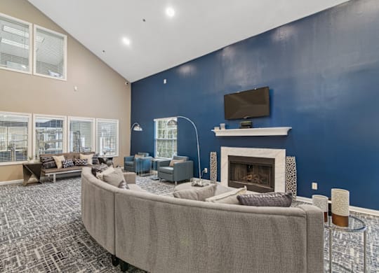 Clubhouse lounge area with couch and a TV above the fireplace at Woodmere Trace apartments in Duluth, GA
