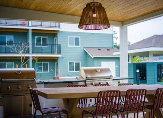 A patio with a table, chairs, and a grill.
