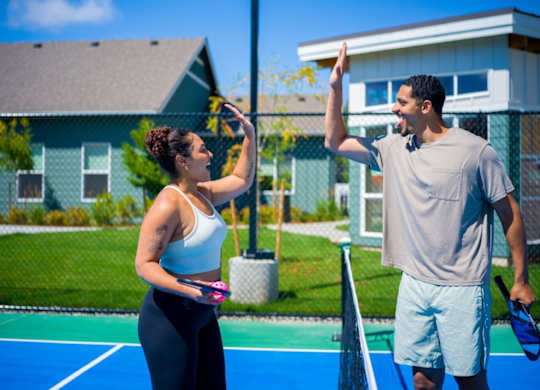 A man and woman playing tennis on a blue court.