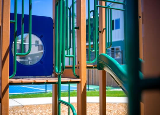 A playground with a blue slide and a green slide.