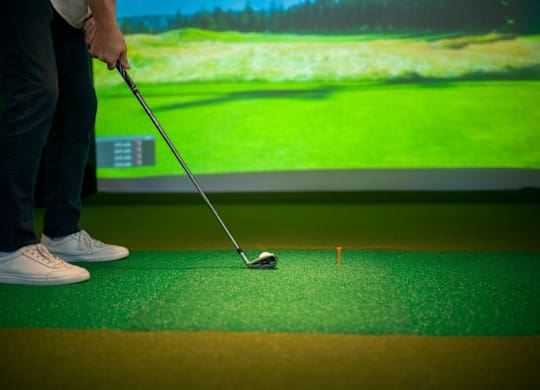 A man is practicing golf on a green mat.