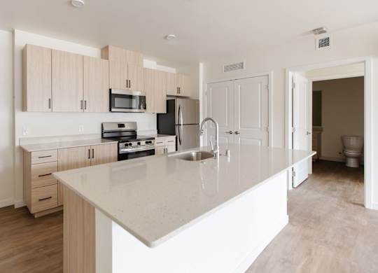 A kitchen with a white countertop and wooden cabinets.