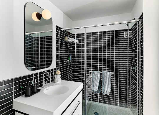 A bathroom with a white sink and black tiles.