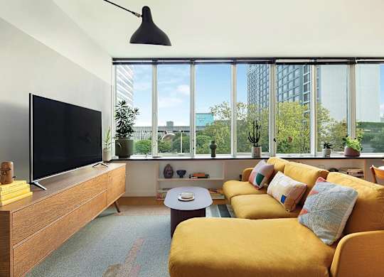 A living room with a yellow couch and a flat screen TV.