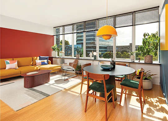 A living room with a red wall and a table with four chairs.