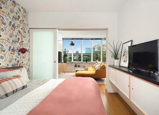 A bedroom with a large bed and a television on the wall.