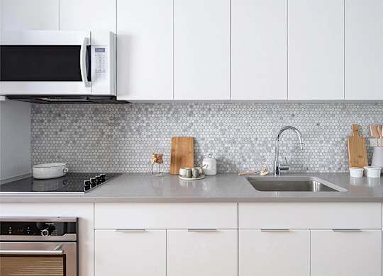 A kitchen with a white microwave, sink, and cabinets.