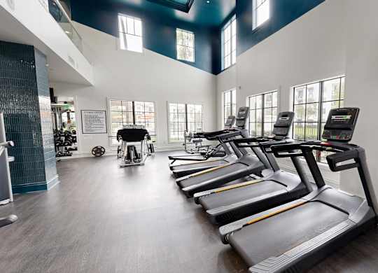A gym with treadmills and a television mounted on the wall.