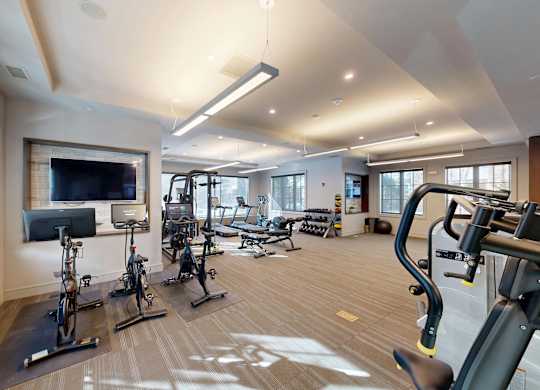 A spacious gym with a variety of exercise equipment and a television.