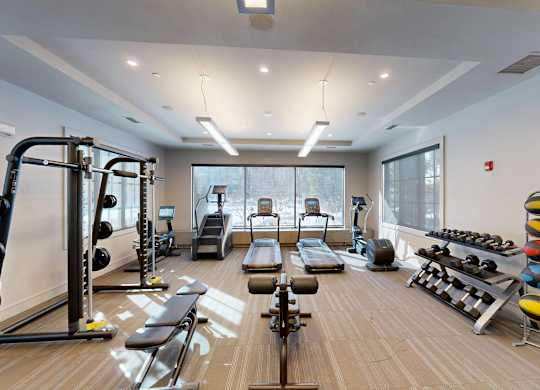 A gym with a variety of equipment including weights, a bench press, and a treadmill.