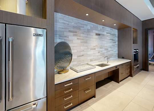 A modern kitchen with a stainless steel refrigerator and wooden cabinets.