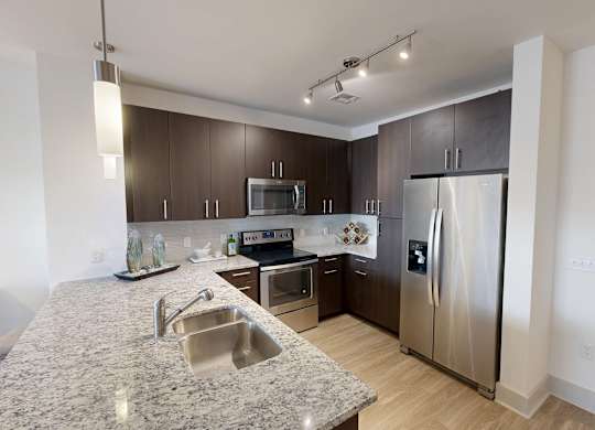 A modern kitchen with granite countertops and stainless steel appliances.