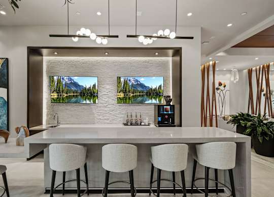 A modern kitchen with a bar area and a view of a mountain landscape on the wall.