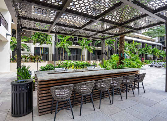 A patio with a bar and chairs under a pergola.