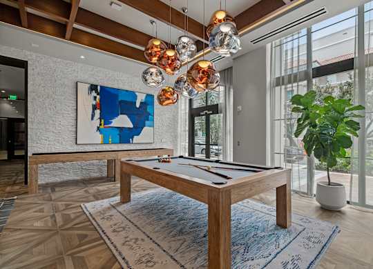 A pool table in a room with a large window and a potted plant.
