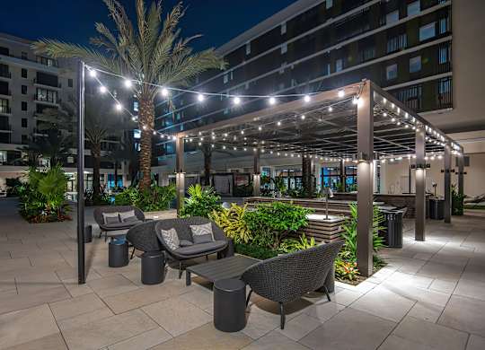 A patio area with a table and chairs under a lit canopy.