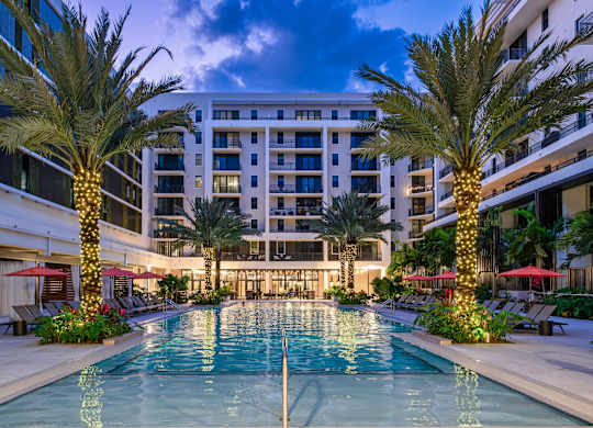 A large pool surrounded by palm trees and lounge chairs.