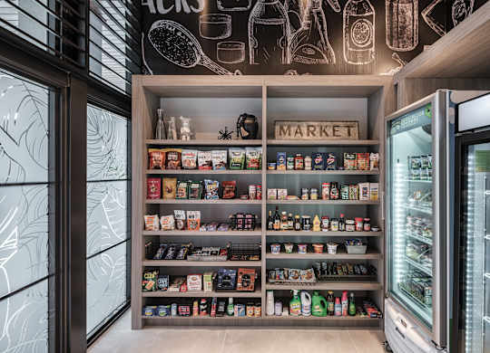 A refrigerator and shelves with various food items in a kitchen.
