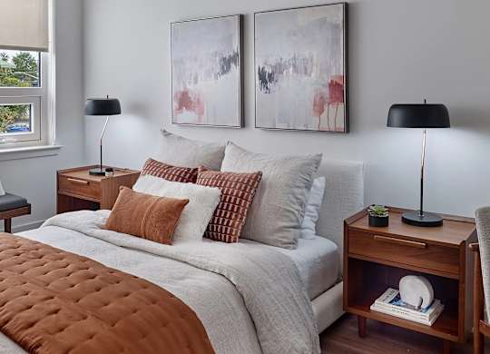 A bedroom with a large bed and two lamps.
