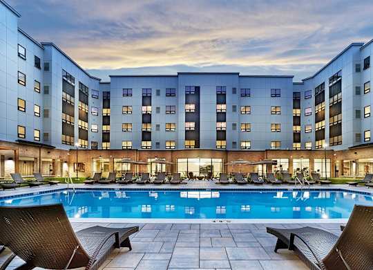 A large swimming pool in front of a multi-story residential building.