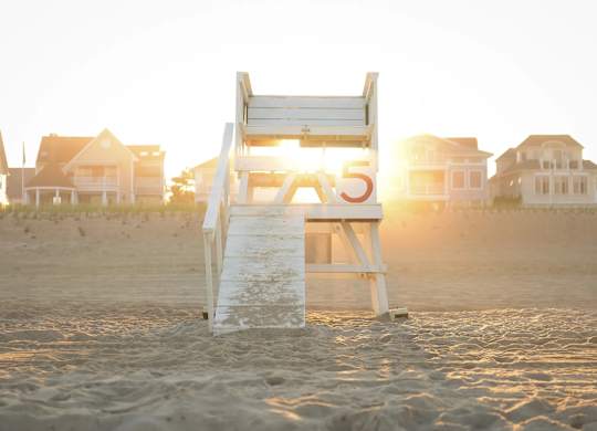 A lifeguard chair with the number 5 on it is on a beach.