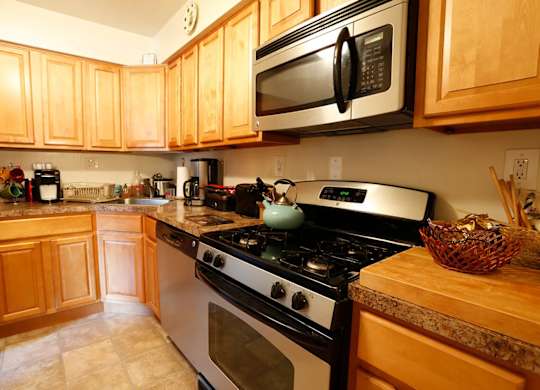 A kitchen with a stove, oven, microwave, and cabinets.