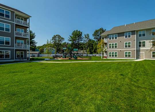 A large grassy field in front of apartment buildings.