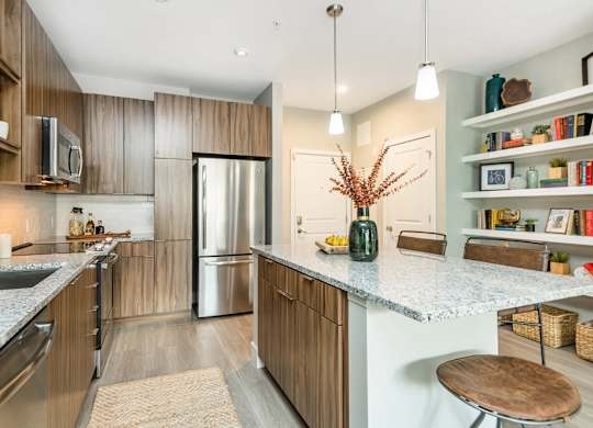A kitchen with a refrigerator, microwave, and wooden cabinets.