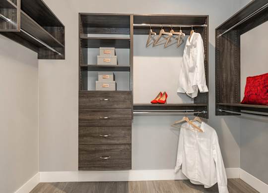 A white shirt is hanging on a wooden hanger in a closet.