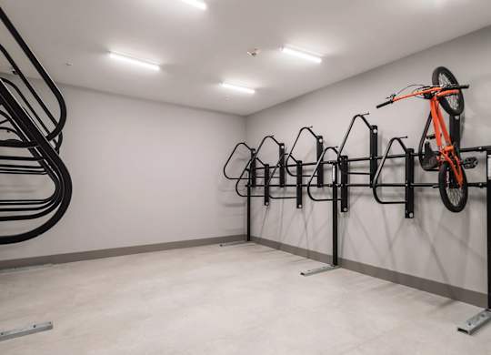 A bike rack with multiple bikes, one orange, in a white room.