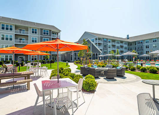 A sunny day at the outdoor seating area of a hotel with orange umbrellas and tables.