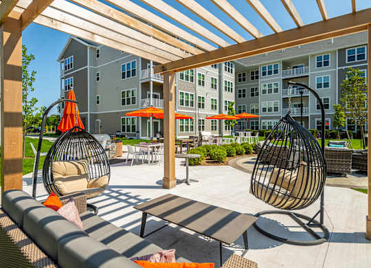 A patio with a white table and two hanging chairs.