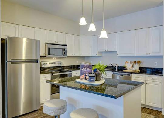 A kitchen with a refrigerator, microwave, and bar stools.