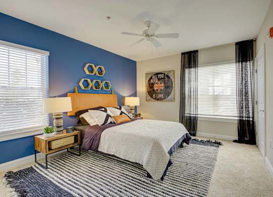 A bedroom with a bed, nightstand, and a ceiling fan.