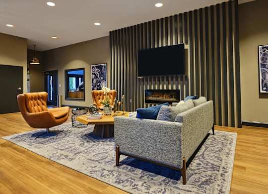 A living room with a grey couch, a brown chair, and a television mounted on the wall.