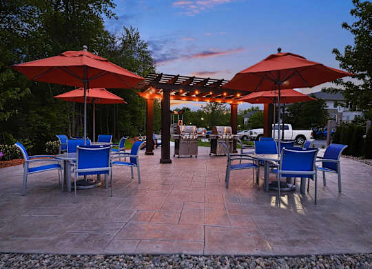 A patio with tables and chairs under red umbrellas.