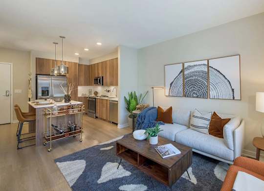A modern living room with a white sofa, a coffee table, and a kitchen area in the background.