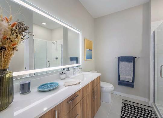 A bathroom with a white counter top and a glass shower door.