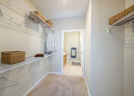 A walk-in closet with white shelves and a basket on the shelf.