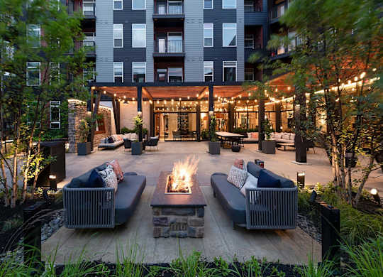 A modern outdoor seating area with a fire pit in the center.