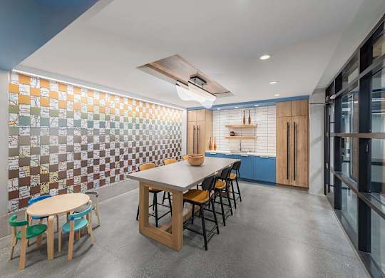 A kitchen with a table and chairs in front of a tiled wall.