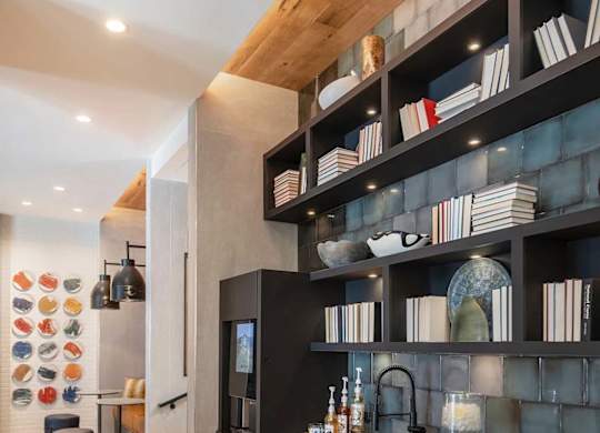 A modern kitchen with a black countertop and wooden shelves.