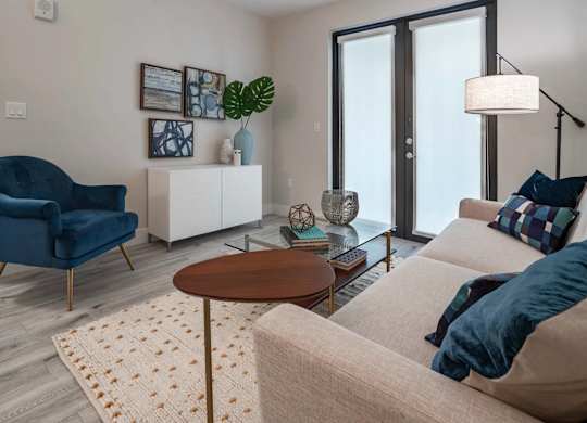 A living room with a blue chair, a white sofa, and a wooden table.