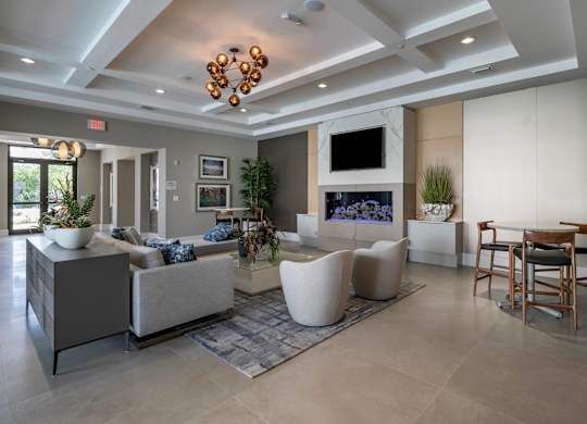 A modern living room with a grey sofa, a white armchair, a TV, and a fireplace.