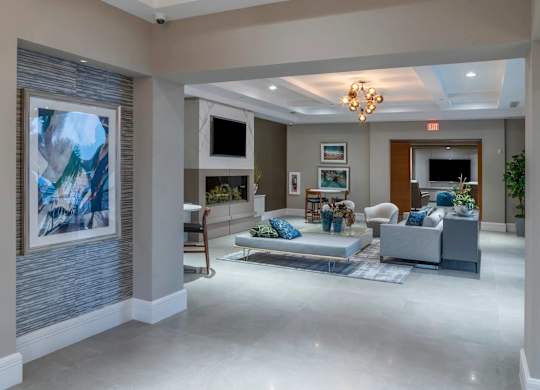 A spacious living room with a grey sofa set and a large abstract painting on the wall.